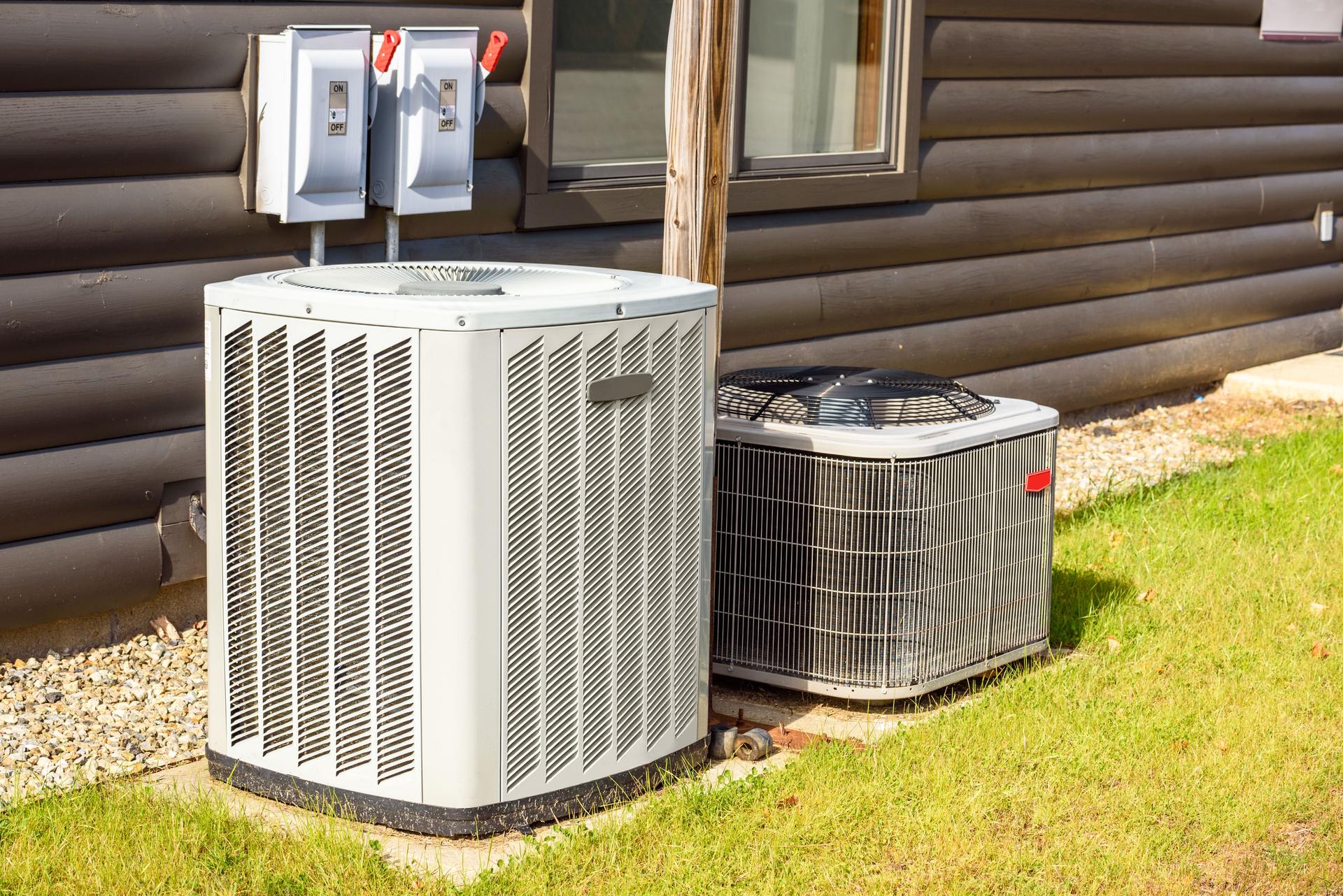 Air conditioning and heating system external units at the back of a house on a sunny autumn day